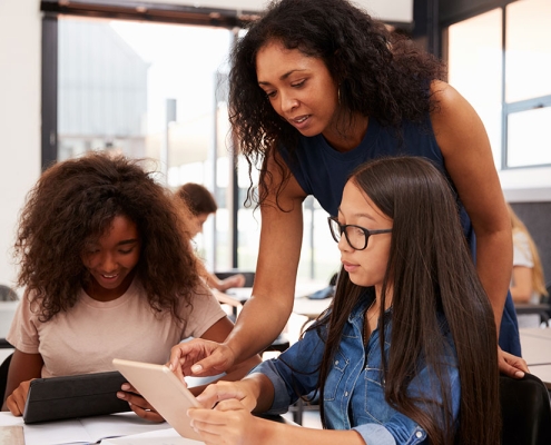 Teacher helping high school students with technology